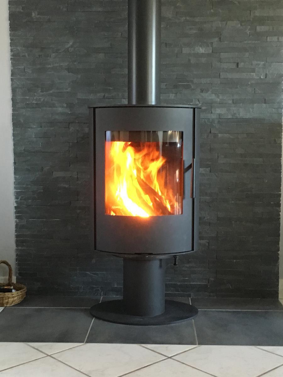 - Installation d'un poêle à bois ROMOTOP Evora T, finition acier, appareil rotatif à 360°, avec un foyer pour bûches de 33 cm.